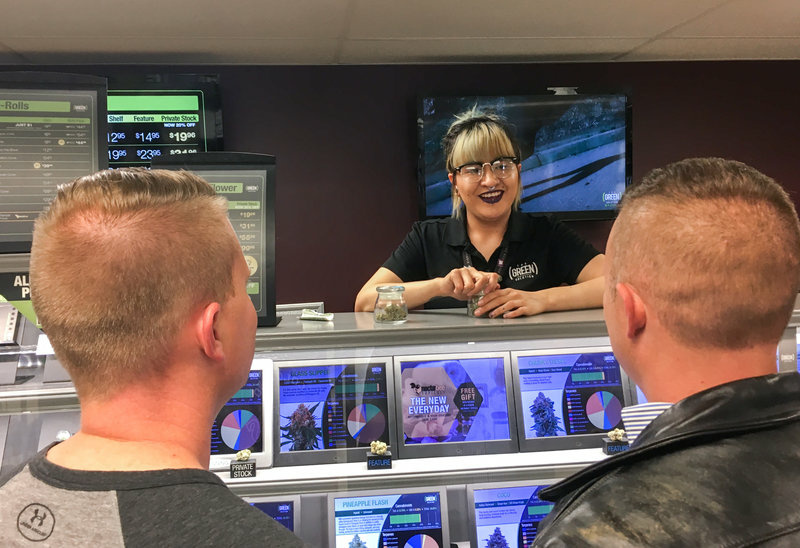 Yessenia Hinojos, a budtender at a Denver cannabis dispensary called The Green Solution, describes marijuana strains to A.J. Tarantino (left) and Philip Gurley. Both men are officers with Colorado State Patrol. Yessenia Hinojos, a budtender at a Denver cannabis dispensary called The Green Solution, describes marijuana strains to A.J. Tarantino (left) and Philip Gurley. Both men are officers with Colorado State Patrol.