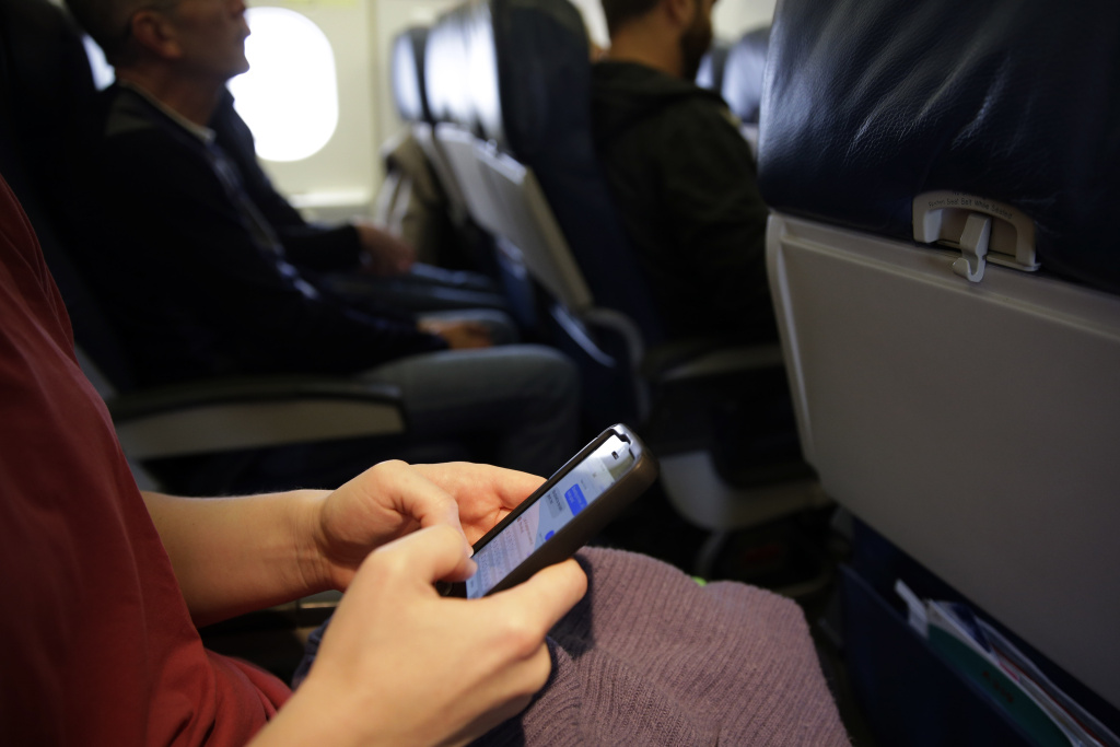 Cellphones Planes In this Oct. 31, 2013, file photo, a passenger checks her cell phone before a flight in Boston. Federal regulators said Thursday, Nov. 21, 2013, that rules against making cellphone calls during airline flights are