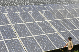 A man walks past solar modules of a newly installed photovoltaic complex near the village Denkendorf, southern Germany, on July 1, 2010.