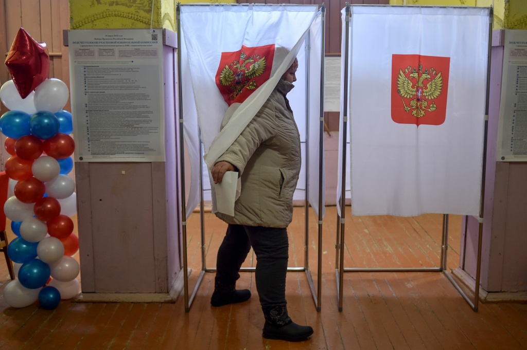 RUSSIA-POLITICS-VOTE A woman walks out of a voting booth at a polling station during Russia's presidential election in the village of Borok on March 18, 2018.