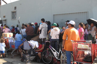 Californians stand in a long line at Helping One Another Progress, a church-run food bank east of downtown Los Angeles. People at the front of the line arrived at 3 a.m. to get a ticket and wait for a single box of groceries.