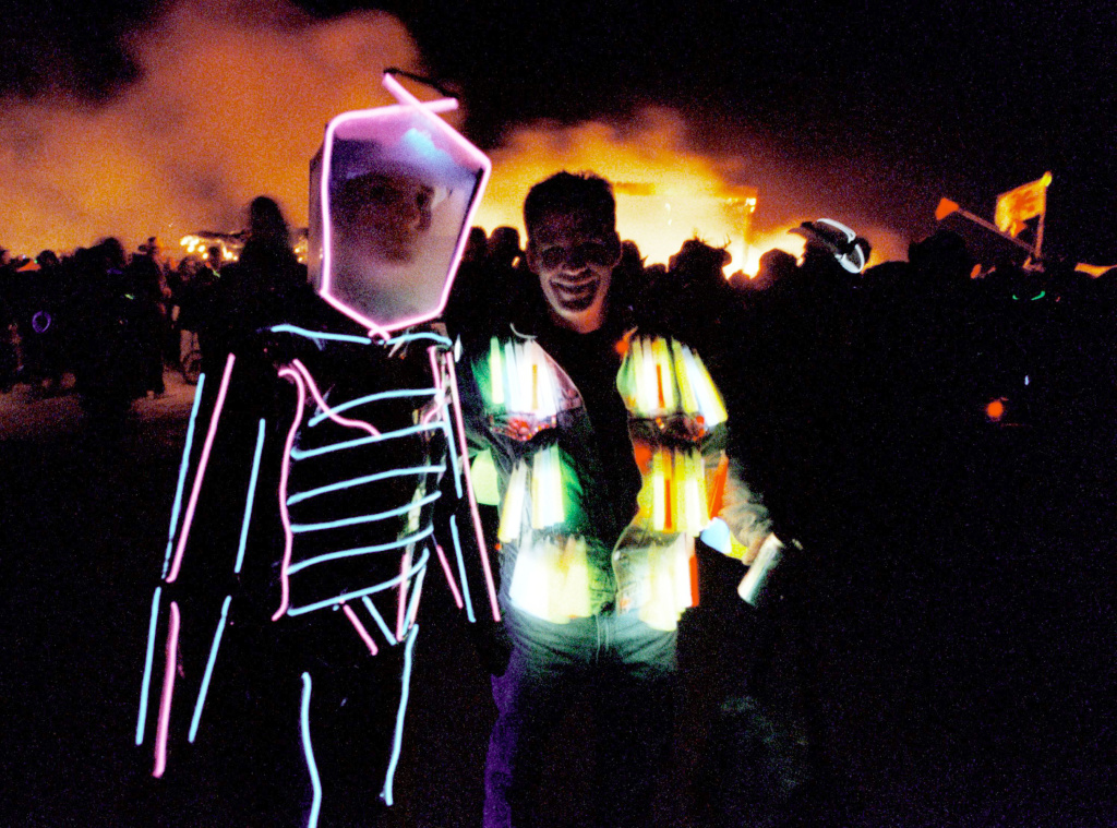 Burning Man Festival in Nevada Desert People wearing illuminated costumes walk past the burning remains of a 52-foot tall wooden man on September 2, 2000 during the15th annual Burning Man festival in the Black Rock Desert near Gerlach, Nevada.