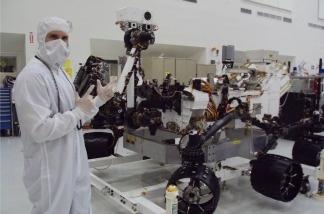 NASA engineer Matt Horner wearing a 'bunny suit.' He's standing in front of Curiosity, the next rover to head to Mars.