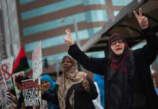A woman waves to passing motorists at a rally in support of Arab anti-goverment protesters on Saturday afternoon outside the Federal Building on Wilshire Blvd.
