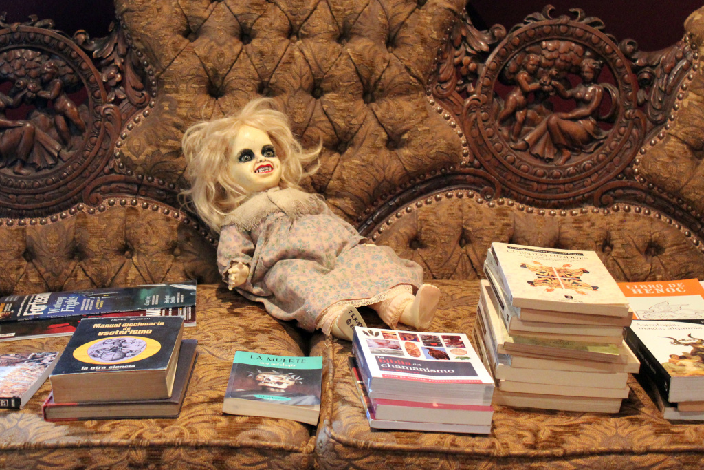 Bleak House doll A couch piled with books and a demonic doll.