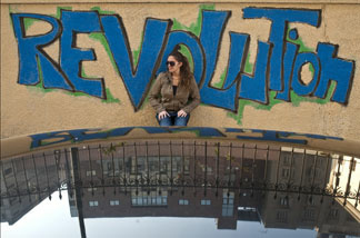 Mercer 15078 An Egyptian woman stands in front of graffiti reading 'Revolution' at Cairo's Tahrir Square, the epicentre of the popular revolt that drove veteran strongman Hosni Mubarak from power after 30 years, on Feb. 17, 2011.