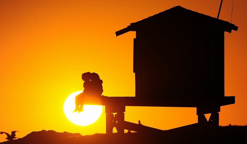 People enjoy the view from a lifeguard structure as the sun sets at Seal Beach, south of Los Angeles on July 9, 2012.