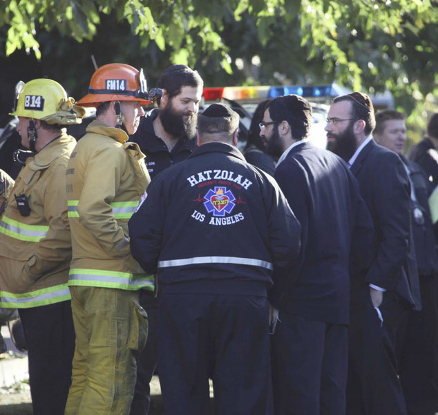 Los Angeles firefighters and synagogue parishioners huddle at the scene in Los Angeles where a gunman shot and wounded two men in the parking garage of a North Hollywood synagogue early Thursday, Oct. 29, 2009. Jewish schools and temples were put on alert in case it was not a lone attack, authorities said.