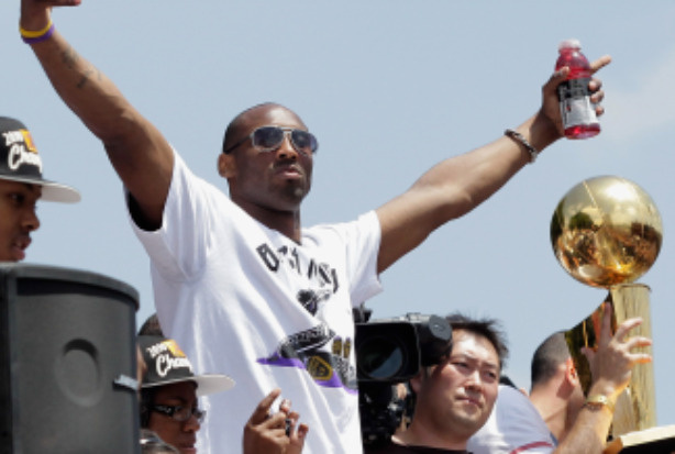 Los Angeles Lakers guard Kobe Bryant (L) waves to the crowd while riding in the victory parade for the the NBA basketball champion team on June 21, 2010 in Los Angeles, California.