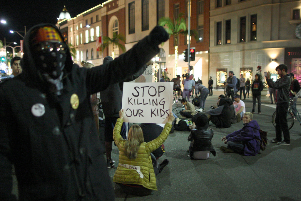 Protesters In LA React To Grand Jury Decision In Ferguson Case LOS ANGELES, CA - NOVEMBER 24: Protesters block traffic at the intersection of Wilshire Boulevard and Rodeo Dr. in Beverly Hills after marching from Leimert Park in reaction to the grand jury decision not to indict a white police officer who had shot dead an unarmed black teenager in Ferguson, Missouri on November 24, 2014 in Los Angeles, California. Police officer Darren Wilson shot 18-year-old Michael Brown on August 9, sparking large ongoing protests. (Photo by David McNew/Getty Images)