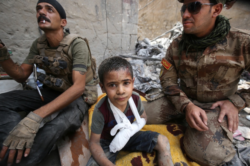 IRAQ-CONFLICT Omar, a wounded Iraqi boy whose family was killed in the battles to oust the Islamic State from Mosul, sits with members of the Counter Terrorism Services as they help him flee the Old City of Mosul on July 3, 2017.