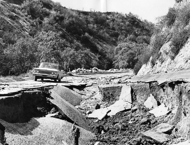 1938: People walk along the flooded L.A. River near the Dayton Avenue Bridge. In the background, a railroad bridge hangs in a twisted heap after one of the pilings has collapsed. (Photograph courtesy of the Los Angeles Public Library)