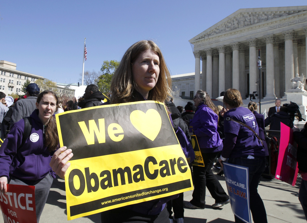 Obamacare Whats in a Name Holding a sign saying