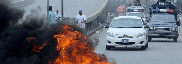 Pakistani policemen patrol on vehicles after overnight violence in Karachi, where dozens of vehicles and shops were set ablaze as security forces struggled to regain control.