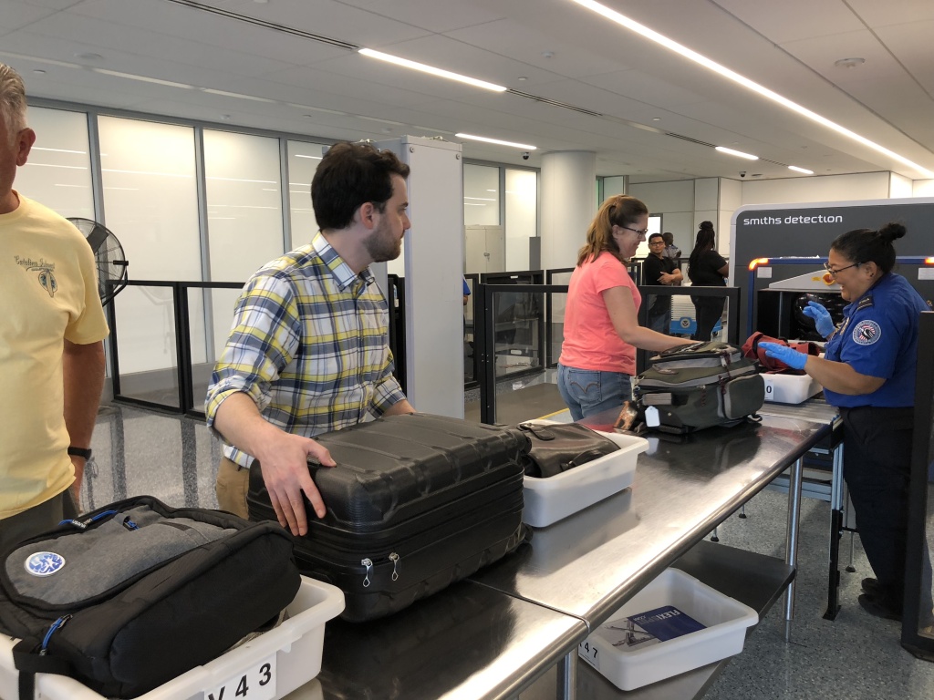 Passengers prepare their carry-on luggage for the new 3D scanner. Passengers prepare their carry-on luggage for the new 3D scanner.