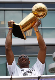 Los Angeles Lakers guard Kobe Bryant hoists the championship trophy while riding in the victory parade for the the NBA basketball champion team on June 21, 2010 in Los Angeles, California.