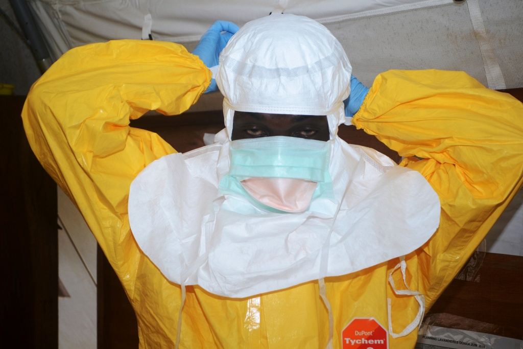 GUINEA-WAFRICA-HEALTH-EPIDEMIC-EBOLA A picture taken on June 28, 2014 shows a member of Doctors Without Borders (MSF) putting on protective gear at the isolation ward of the Donka Hospital in Conakry, where people infected with the Ebola virus are being treated.