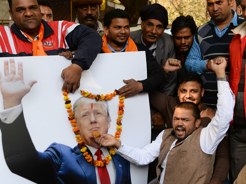 Vishnu Gupta (right), head of India's Hindu Sena group, offers sweets to a garlanded poster of Trump in New Delhi on Thursday. Vishnu Gupta (right), head of India's Hindu Sena group, offers sweets to a garlanded poster of Trump in New Delhi on Thursday.