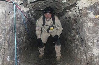 In this Thursday, Nov. 25, 2010 photo released by U.S. Immigration and Customs Enforcement (ICE), a task force agent crouches inside a cross-border tunnel that authorities say was used as an underground drug passage, in San Diego. The tunnel found Thursday is 2,200 feet long, more than seven football fields, and runs from the kitchen of a home in Tijuana, Mexico, to two warehouses in San Diego's Otay Mesa industrial district, said Mike Unzueta, head of investigations at U.S. Immigration and Customs Enforcement in San Diego.