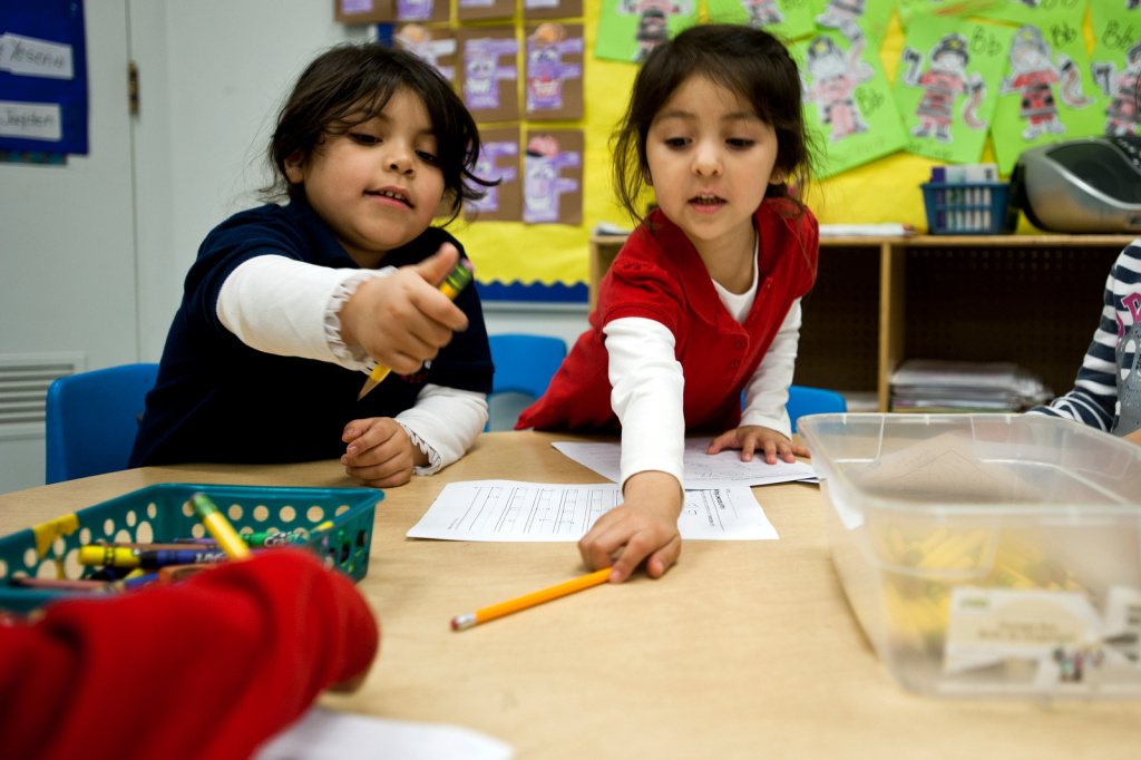 Dual Language API - 5 Transitional kindergarten students Adamaris Duran, left, and Sophia Lopez reach for pencils to begin a writing exercise.