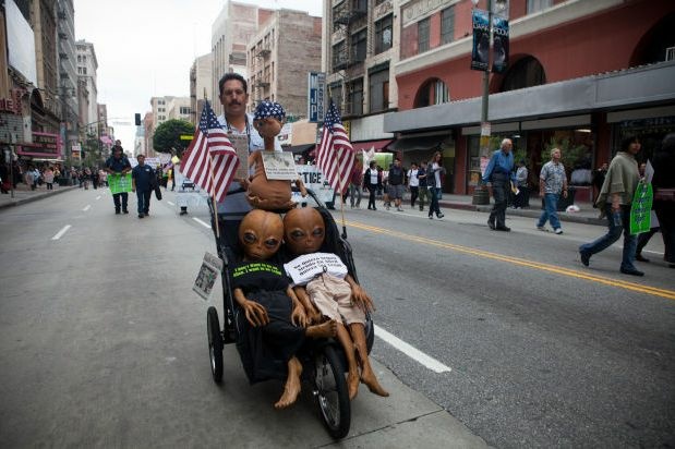 A protester wheels "aliens," including an E.T. doll, down the street in downtown Los Angeles, May 1, 2012